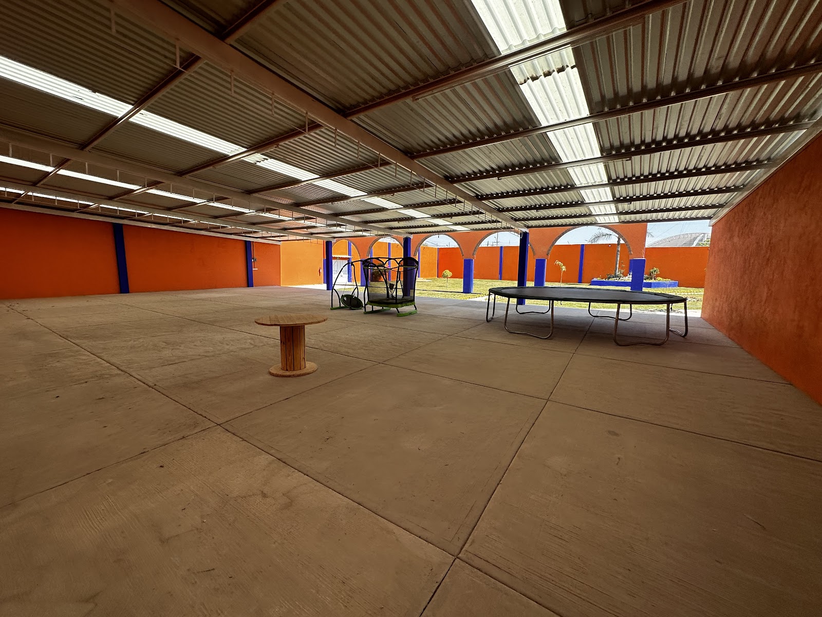 Área techada del salón, amplia y despejada, con juegos para niños al fondo